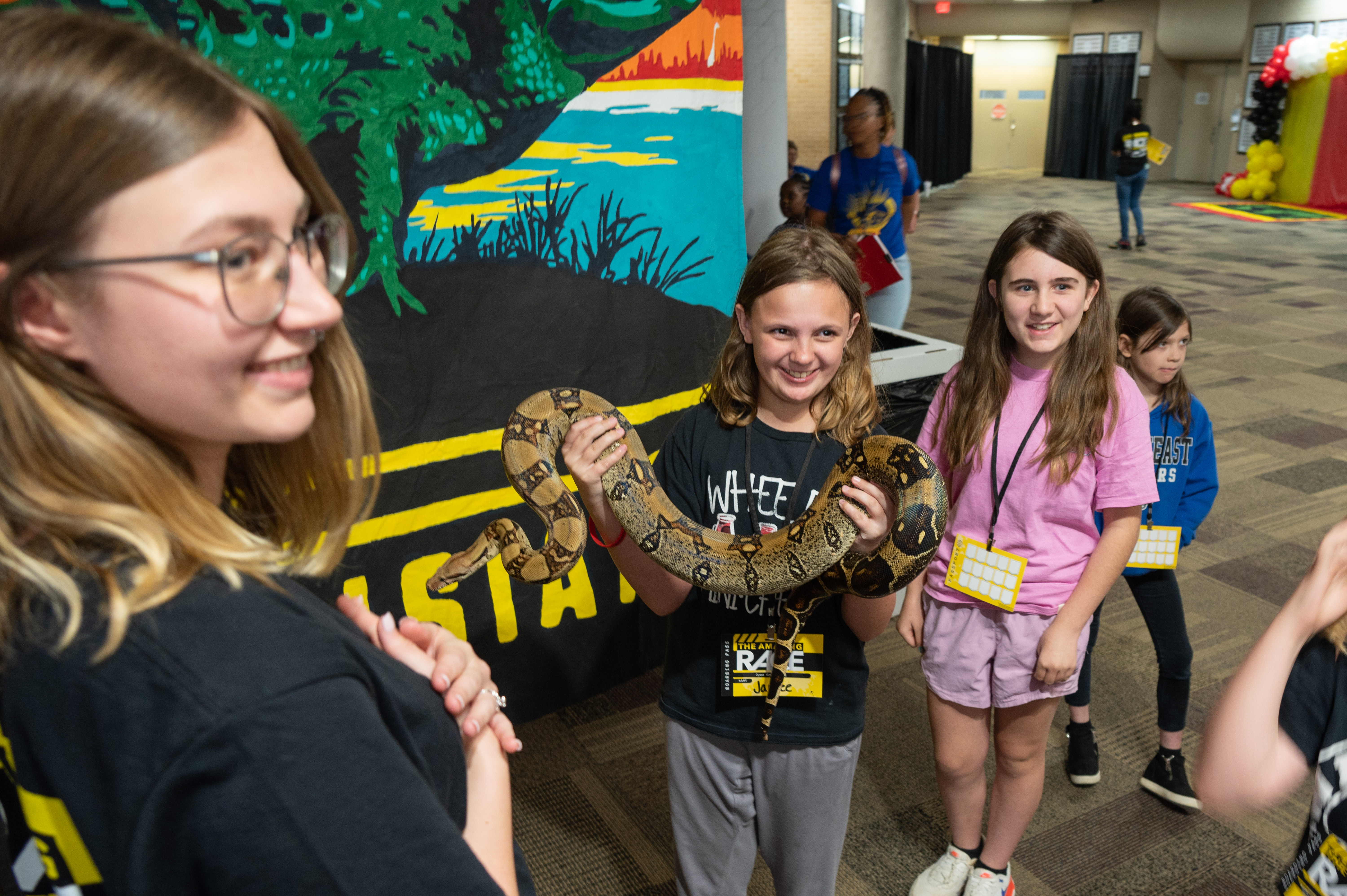 Students at Open House smile while holding a snake