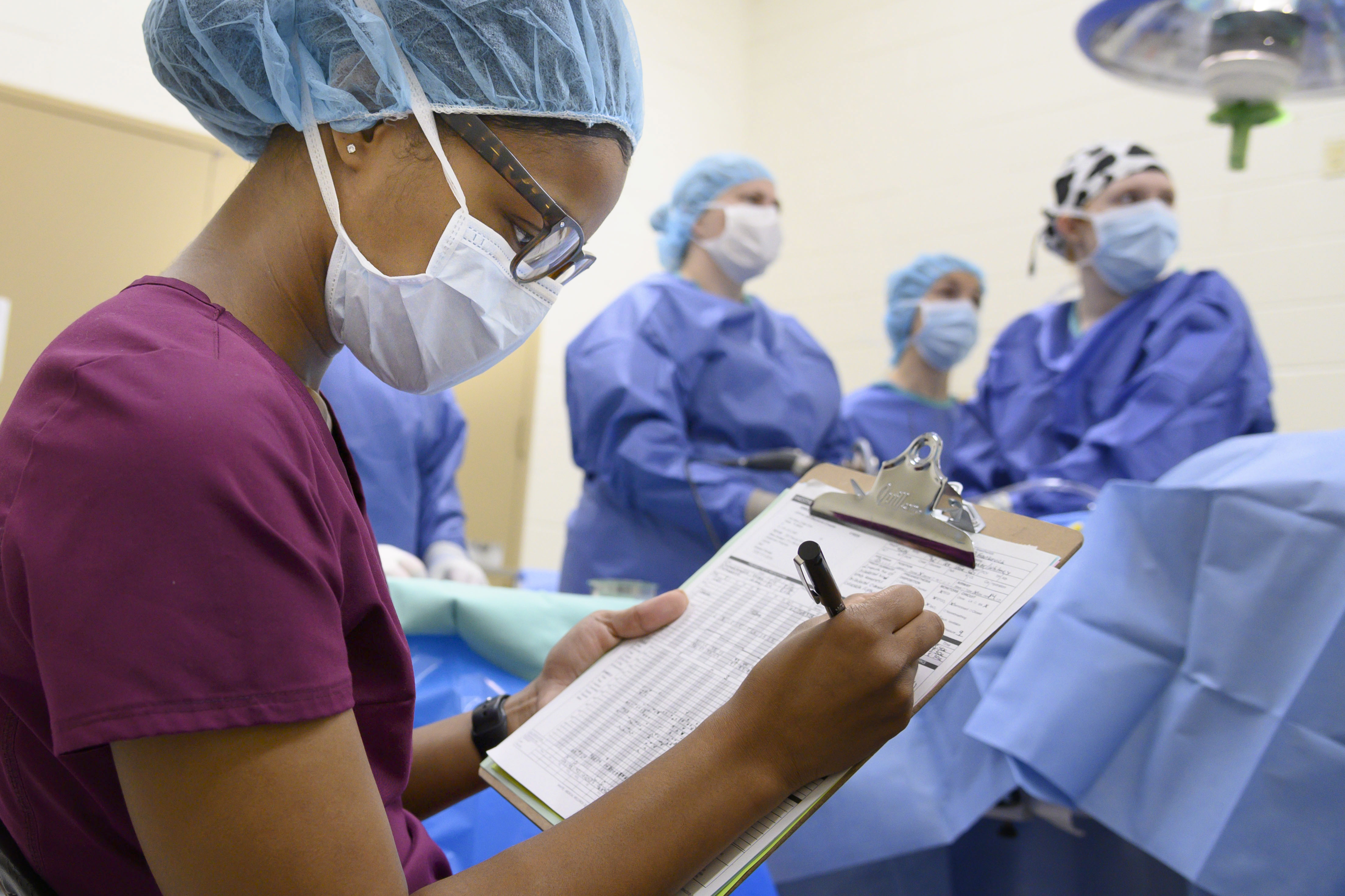 A technician takes notes during surgery